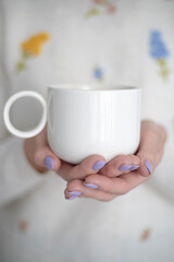 A cup of morning coffee in female hands and flowers on a white background