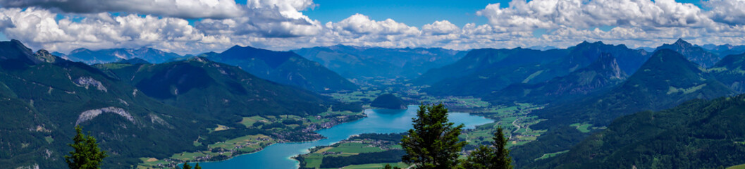 View of Wolfgangsee lake and surrounding Alps mountains from Zwolferhorn mountain in Salzkammergut region, Austria. Spectacular view from a mountain peak on a clear sunny day with blue sky.