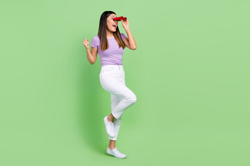Full body length photo of young funky vietnamese girl fist up enjoy exploring tourist with binoculars isolated on green color background