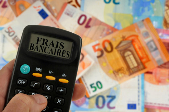 Concept de frais bancaires avec une calculatrice avec des billets de banque en euros au second plan