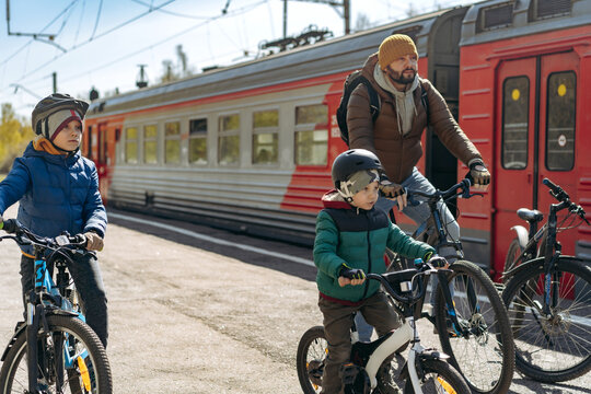man and children on bicycles on train station travelling to countryside