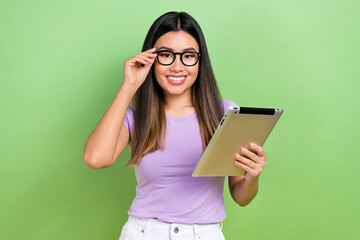 Photo portrait of pretty japanese korean young girl hold tablet touch specs wear trendy purple outfit isolated on green color background