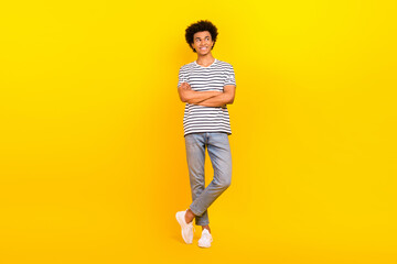 Fototapeta na wymiar Full body photo of young businessman wear striped t-shirt denim jeans crossed arms look empty space isolated on yellow color background