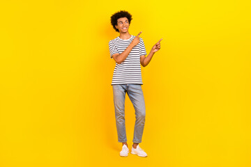 Full length photo of youngster man wear striped t-shirt jeans look direct fingers copyspace price ad isolated on yellow color background