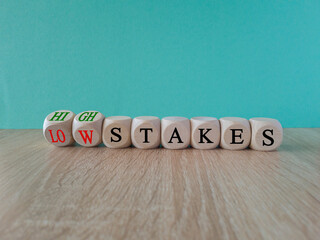 High or low stakes symbol. Concept red words High stakes and Low stakes on wooden cubes. Beautiful wooden table blue background. Business high or low stakes concept. Copy space.