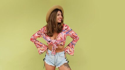 In the image, a woman is featured in a summer-inspired crop top and denim shorts. She is standing...