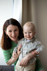 young brunette woman mother with a little blond toddler boy look at the camera and smile