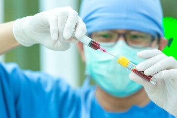 The doctor with a syringe of blood sample and a rack with other samples. Technician holding blood syringe sample for study.