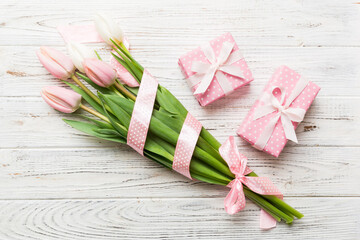 Pink tulips flowers and gift or present box on colored table background. Mothers Day, Birthday, Womens Day, celebration concept. Space for text top view
