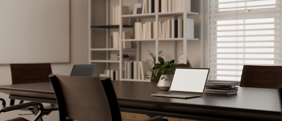 A laptop mockup on a meeting table in modern minimal meeting room.
