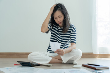 Stressed and headache asian woman with large bills or invoices no money to pay to expenses and credit card debt. shortage, Financial problems, mortgage, loan, bankruptcy, bankrupt, poor, empty wallet