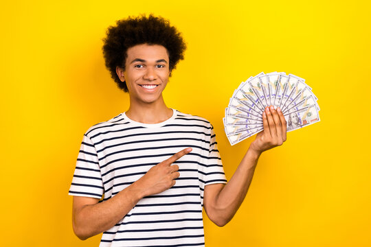 Photo of funny chevelure hair young guy wear t-shirt point finger much money dollars banknotes casino winner isolated on yellow background - Powered by Adobe