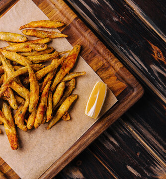 wooden board of fried whitebait with slices of lemon
