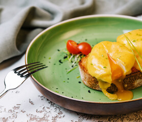 Classic egg benedict on green plate