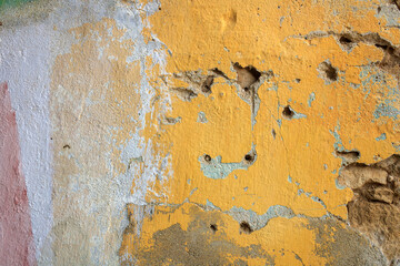 Texture of old cracked scratched yellow stucco wall  