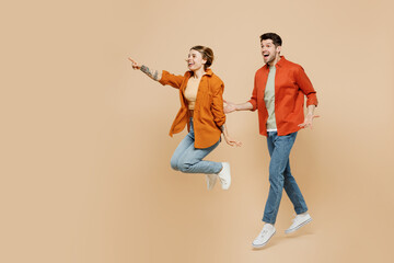 Full body young couple two friends family man woman wear casual clothes together jump high point index finger aisde on workspace area isolated on pastel plain beige color background studio portrait.