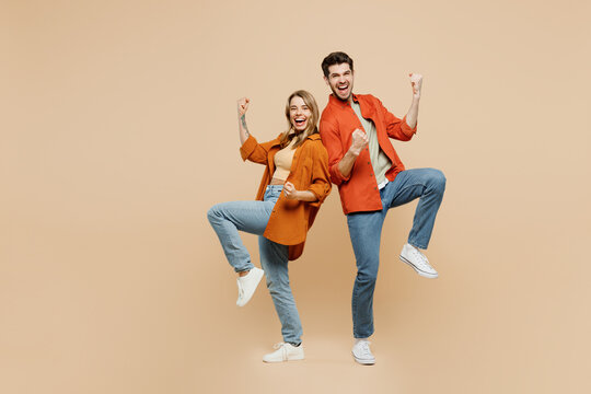 Full Body Young Couple Two Friends Family Man Woman Wear Casual Clothes Together Doing Winner Gesture Celebrate Clenching Fists Say Yes Isolated On Pastel Plain Beige Color Background Studio Portrait.