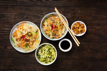 Vegan Rice Noodles with Tofu, Peppers, Carrots on Dark Brown Background