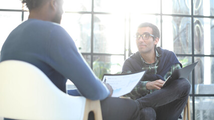 Thoughtful business man in formalwear holding paper while sitting at chair fills out a resume questionnaire in office