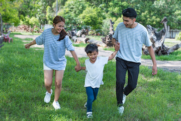 Image of young Asian family playing together at park