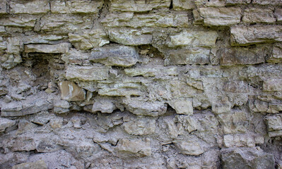 Old ruined stone wall. Ancient stones, structure with mold.