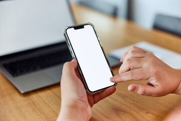 A close-up of hands holding a smartphone and touching a blank white screen with a finger.