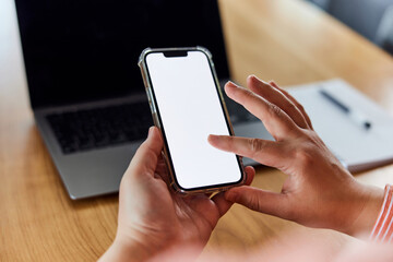 A close-up of a female holding her mobile phone, touching an empty white screen.