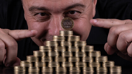 100 Kazakhstani tenge coins stacked in the form of a pyramid and mans face