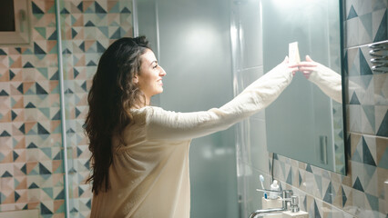 girl takes post it hanging on the bathroom mirror