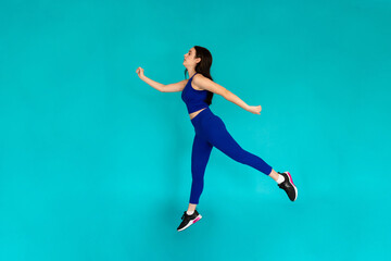 Fototapeta na wymiar Woman jumping in the air in studio shot.