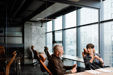Confident mature colleagues talking about contract in office