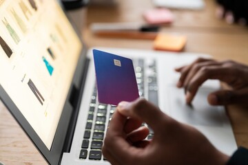 Unrecognizable male using modern laptop while entering credit card credentials into computer during online shopping