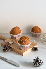 Three muffins on a wooden table.