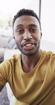 Vertical video of portrait of happy african american man having video call in slow motion