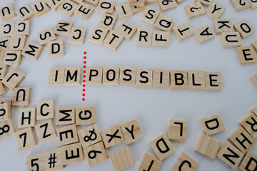close-up square wooden alphabet blocks, word impossible turns into word possible on white...