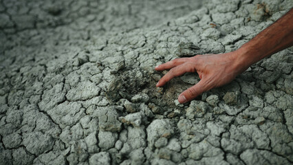 Hand touches dry soil. Close up