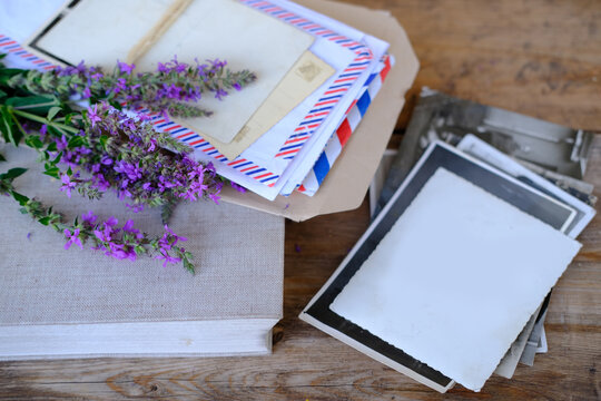 paper book, old photographs, home archive, letter on old wooden table, touching objects of nostalgia, past love, bunch of wild flowers, concept of genealogy, memory of ancestors, family tree