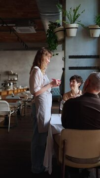 Concentrated blonde waitress writes down order of elderly couple in cafe