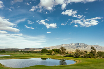 Sierra de Sandía Mountains in front of a field and a lake in New Mexico