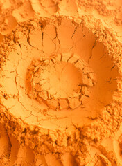 Red terracotta bentonite clay powder texture with cracks. Natural beauty treatment and spa. Clay texture macro, selective focus. Abstract orange background.