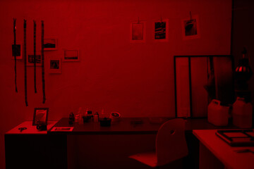 Workplace in darkroom with printed photos and photo film hanging above the table