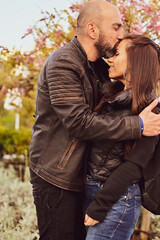 Portrait of happy    smiling  Couple  in love .Bearded man  kissing and hugging  Brunette woman  near   a blooming tree