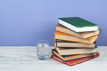 Book stacking. Open book, hardback books on wooden table and blue background. Back to school. Copy space for text.