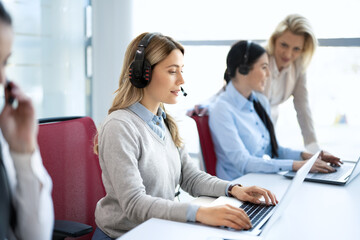 Customer support. Female helpline operator with headphones and laptop at call center.