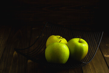 Bowl with green apples on dark wooden background