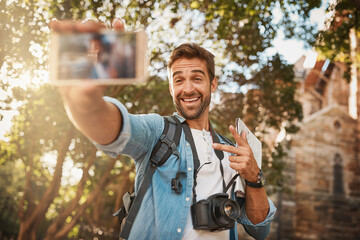 Fototapeta premium Happy man, tourist and peace sign selfie in a city for travel with holiday memory, smile and happiness. Male person outdoor on adventure, journey or vacation photo and freedom with a backpack