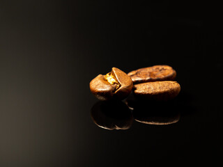 Roasted coffee beans on black glass. Scattered coffee beans. Coffee beans close up.