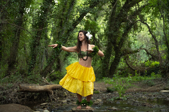 Hawaiian dancer woman dancing hawaiian. Hula dancer in the jungle dancing flowing with the rhythm of the river.