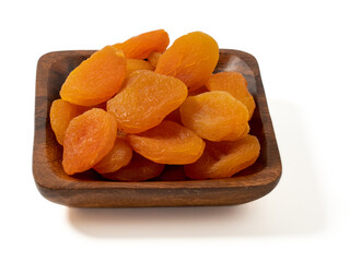 Wooden bowl of dried apricots on a white background, selective focus. Dried apricots close up.