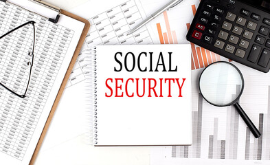 SOCIAL SECURITY text on notebook with clipboard and calculator on a chart background